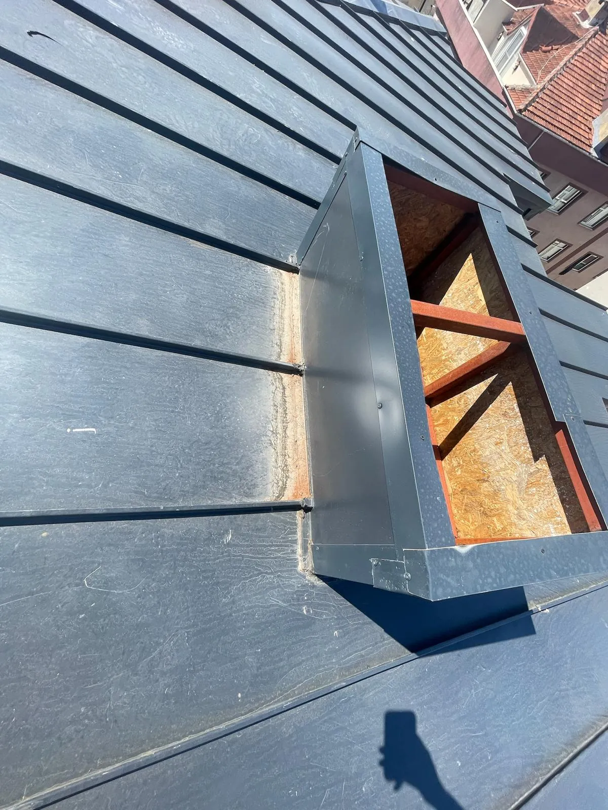 Open joint at a metal-roof chimney junction presenting a weathering risk